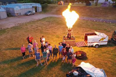 Gruppenbild Jugendlager 2020 - Die Gruppe steht vor dem Brenner des Heißluftballons des Flammen in den Himmel spuckt.
